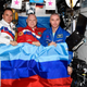 The three astronauts holding up the flag of the Luhansk People’s Republic and the Donetsk People’s Republic.